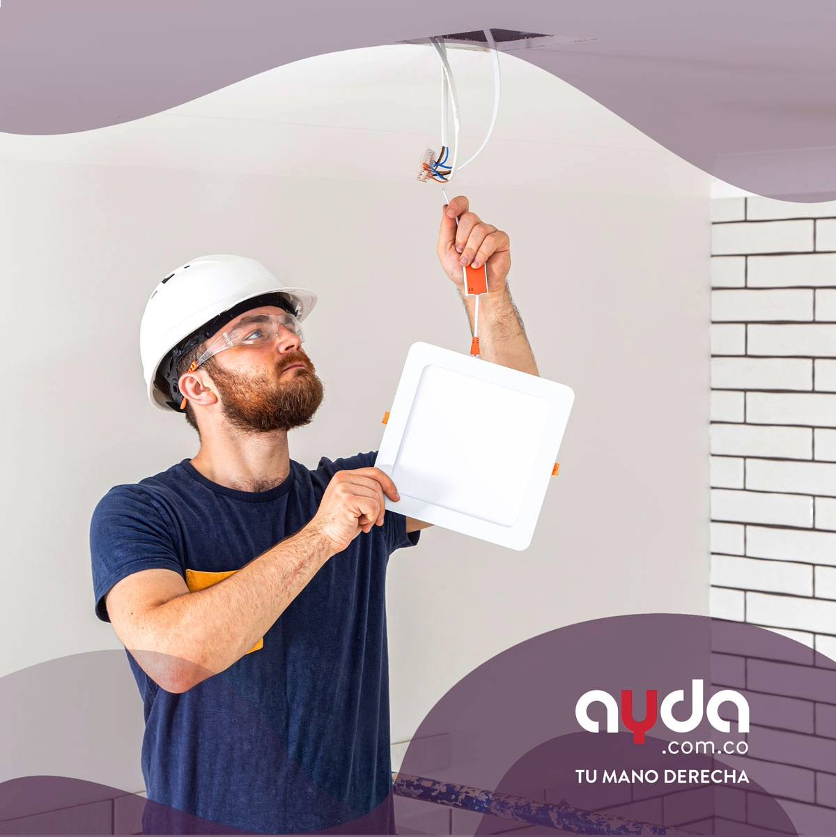 Electricista con casco blanco y gafas de seguridad colocando un tipo de lámparas LED cuadradas empotradas en el techo