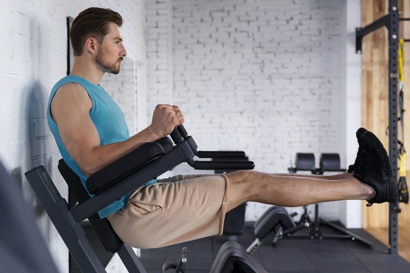 Plano de un hombre durante su rutina de entrenamiento funcional en casa con una máquina para hacer abdominales