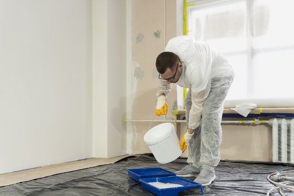 Técnico aplicando pintura blanca en una pared - AYDA