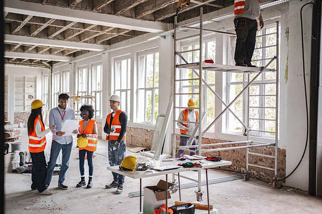  Arquitectos y trabajadores revisando planos y el estado de la obra para asegurar la correcta ejecución del diseño de oficinas modernas 