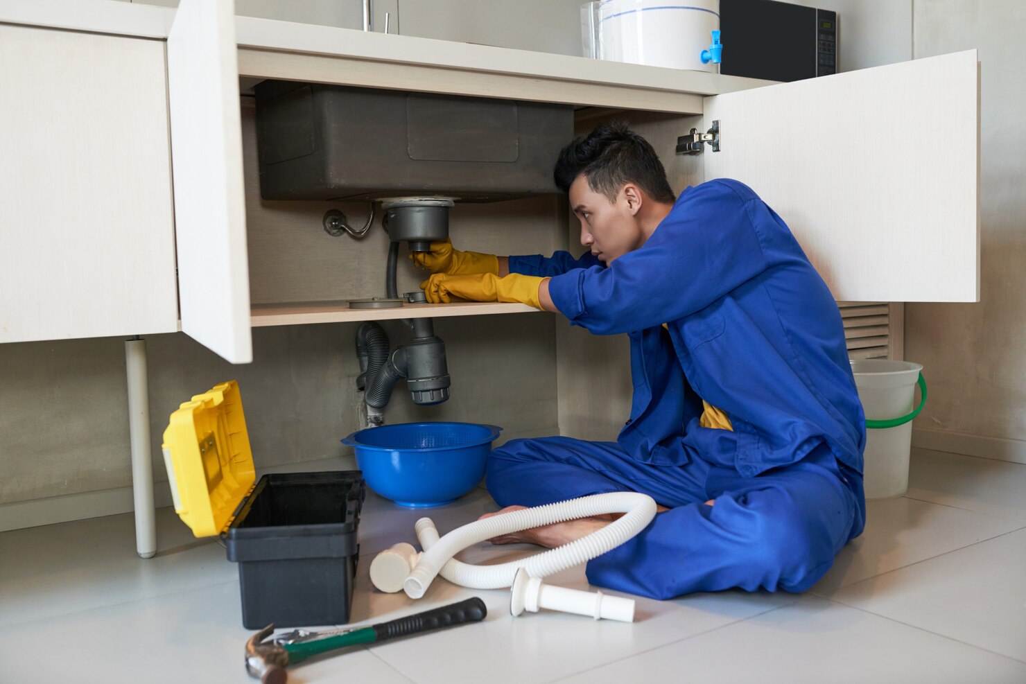 Plomero realizando una reparación de un lavaplatos en la cocina