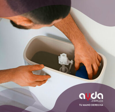 Un plomero profesional con overol verde ajusta los mecanismos internos mientras destapa el inodoro