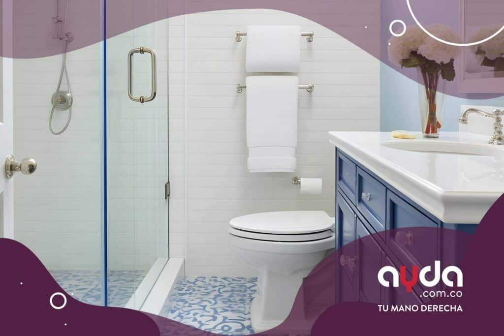 Remodelación de baños pequeños con piso azul de arabescos y mueble de almacenamiento en tono azul oscuro con acabados de baños modernos.