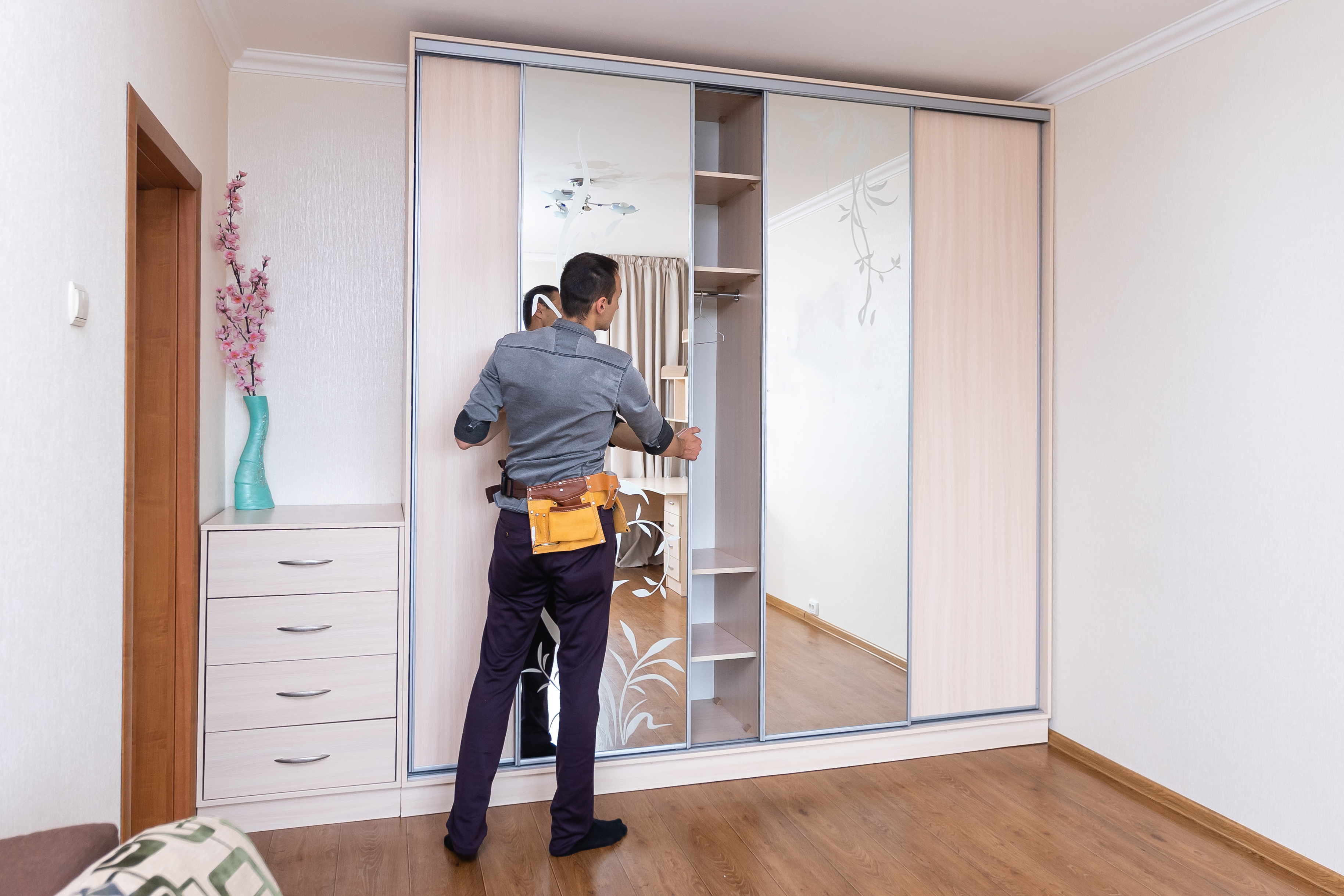  Un instalador profesional coloca las puertas corredizas con espejo en un armario de gran tamaño, una etapa fundamental al aprender cómo armar un clóset funcional 