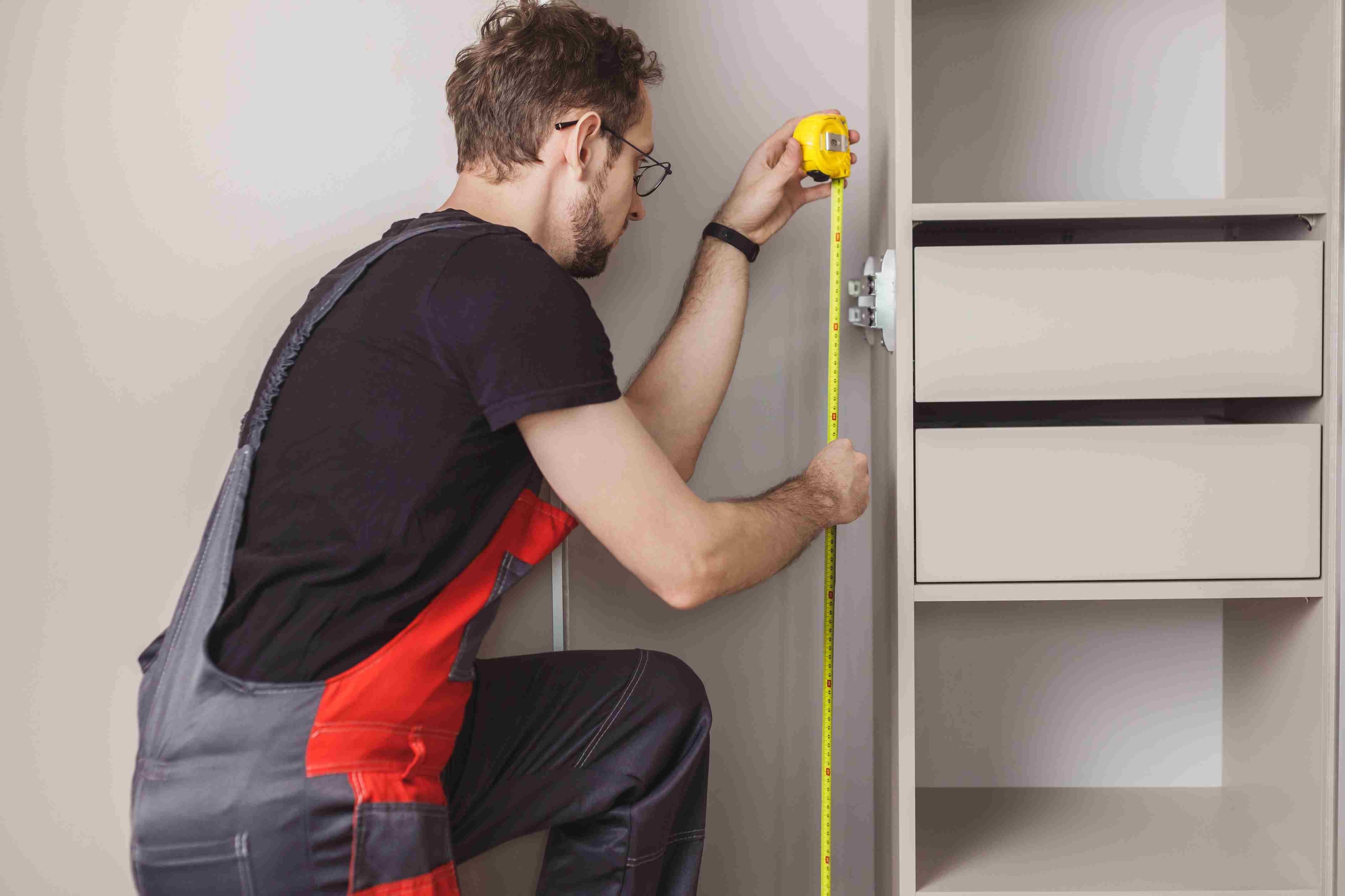 Técnico midiendo con cinta métrica el espacio interior de un closet - AYDA